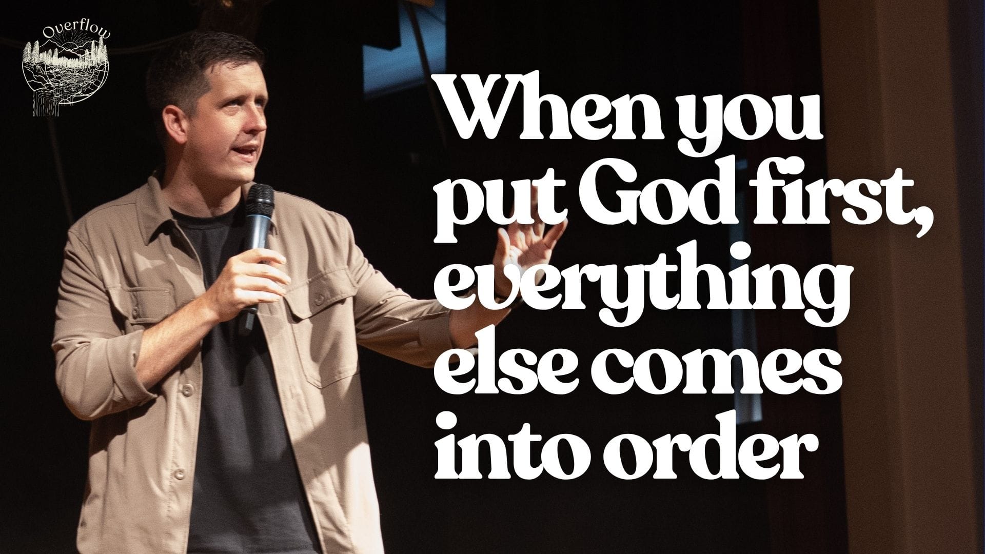 A man, Pastor Josh, stands on a stage holding a microphone, speaking to an unseen audience. He is wearing a light brown collared shirt over a dark t-shirt. The background is dark, with some blurred warm lights. To the right of the image, white text reads: "When you put God first, everything else comes into order". In the top left corner, there is a logo that says "Overflow" with a graphic of mountains and trees.