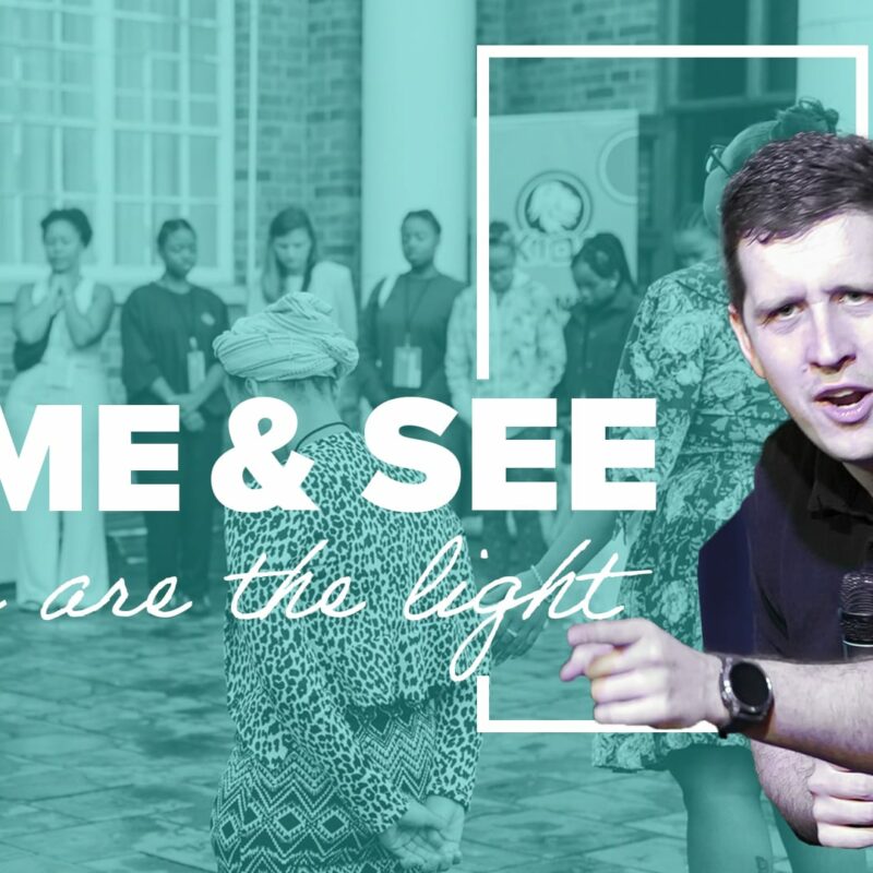 A preacher, Pastor Josh Cooke, is featured in the foreground, speaking passionately into a microphone and gesturing with his hand. The background is a teal-filtered photo of a group of people standing outside a brick building with their eyes closed in what appears to be a moment of prayer or worship. The title of the sermon, "COME & SEE," is written in large white font, and the subtitle, "You are the light," is written below it in a smaller cursive font.