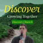 A man with short dark hair in a dark grey collared jacket over a white t-shirt holds a microphone and speaks, looking slightly to his left. He is positioned on the left side of the frame, with a stylized background of green, rolling hills and a dirt path winding through them. The sky is a muted green. Yellow text "Discover" in a script font is prominently displayed in the upper right, with "Growing Together" in a simpler white font below it. At the bottom right, "Discover Church" is written in green script font.