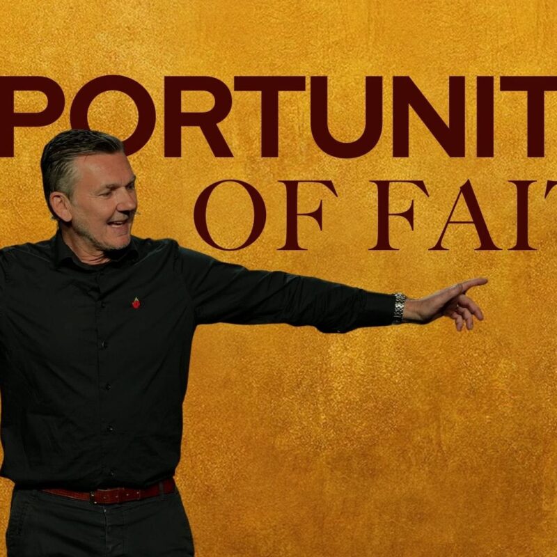 A man with short, styled grey hair and a black collared shirt stands with his arms outstretched, gesturing to his right. He is smiling and looking in the direction he is pointing. Behind him is a textured gold background with the words "OPPORTUNITIES OF FAITH" in dark red capital letters.