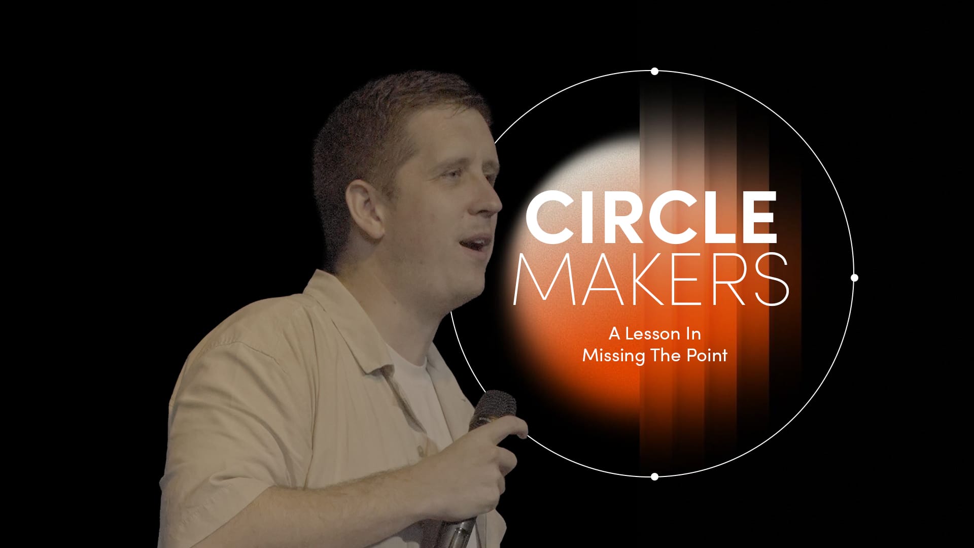 A medium shot of a man, identified as Pastor Josh Cooke, standing on a stage and speaking into a handheld microphone. He is wearing a light-coloured, short-sleeved button-down shirt over a white t-shirt and is holding a book, likely a Bible, in his other hand. To his right, a large graphic overlay features a white circular border with the words "CIRCLE MAKERS" in bold, white sans-serif lettering. Below the title, the text reads, "Praying circles around your biggest fears and greatest dreams". The background is dark with a soft, orange-to-black vertical gradient glow on the right side.