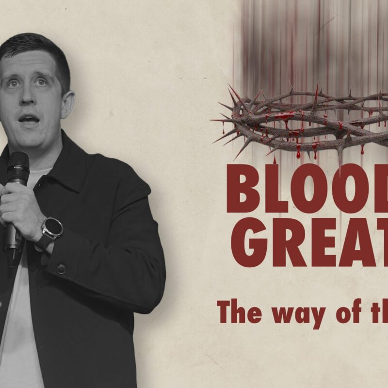 Pastor Josh speaking into a microphone, positioned next to a graphic of a crown of thorns dripping with blood. The text on the right reads "BLOOD IS GREATER" in large red letters, with "The way of the cross" written in a smaller font below it.