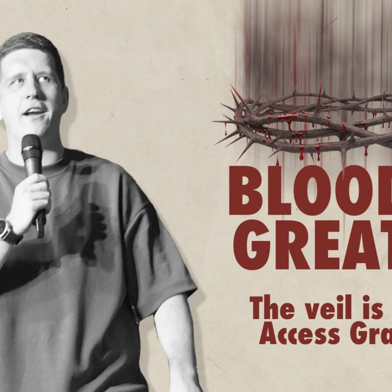 A medium shot of Pastor Josh Cooke speaking during a church service. He is on the left, holding a microphone and looking upward with an expectant expression. On the right, large bold text reads "BLOOD IS GREATER" above the subtitle "The veil is torn; Access Granted". Above the text is a graphic illustration of a crown of thorns with blood dripping from it. The background is a neutral, textured beige.